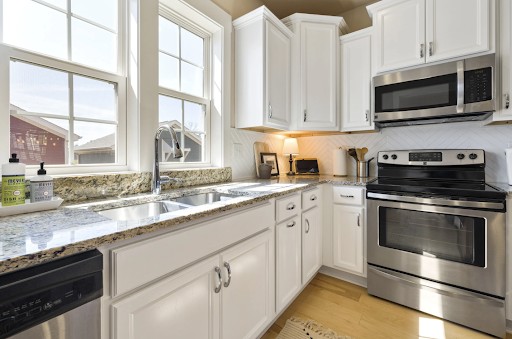 A white theme kitchen area with a window and microwave